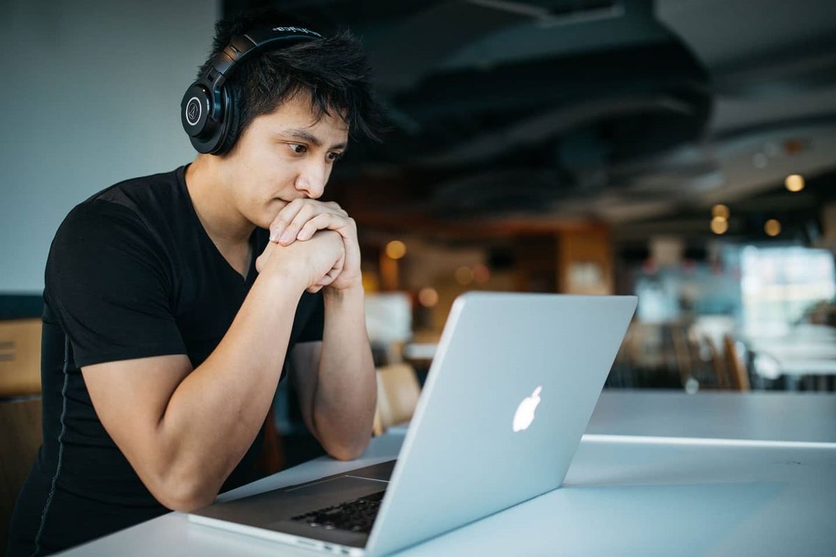 a person sitting at a table using a laptop computer