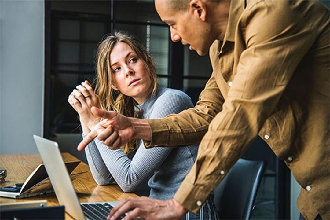a man and a woman sitting at a table using a laptop