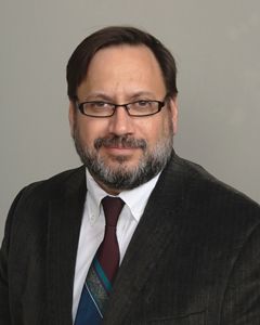 a man wearing a suit and tie smiling at the camera